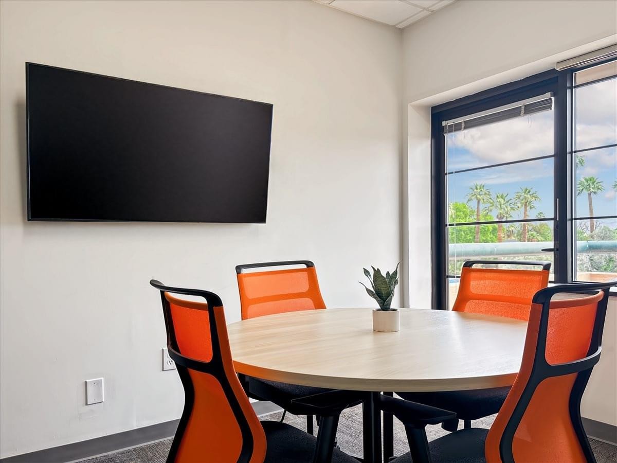 Meeting room at 2025 North 3rd Street featuring a round table, orange chairs, and a large wall-mounted screen.