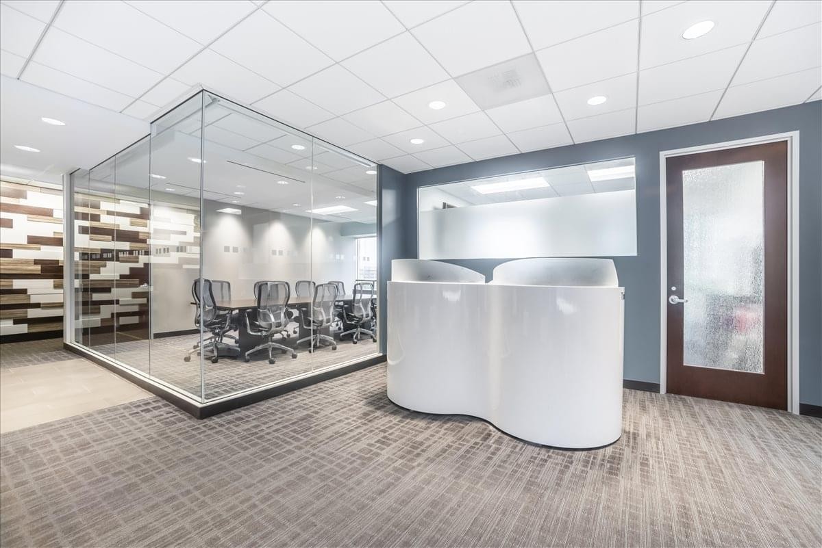 Bright reception area featuring a unique curved white front desk and glass-walled meeting room.