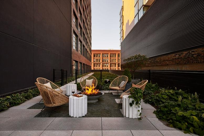 Outdoor rooftop terrace at 208 N Green St featuring a fire pit and wicker seating.