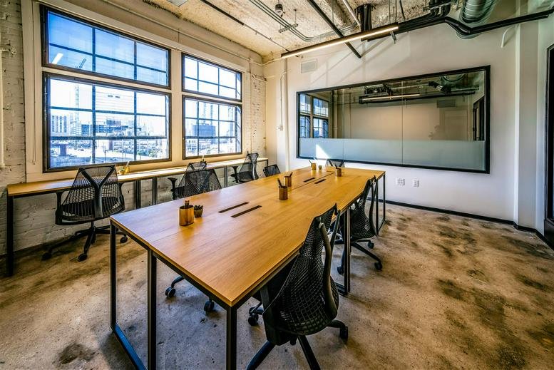 Spacious open-plan workspace at 209 10th Avenue South featuring wooden tables and large windows.
