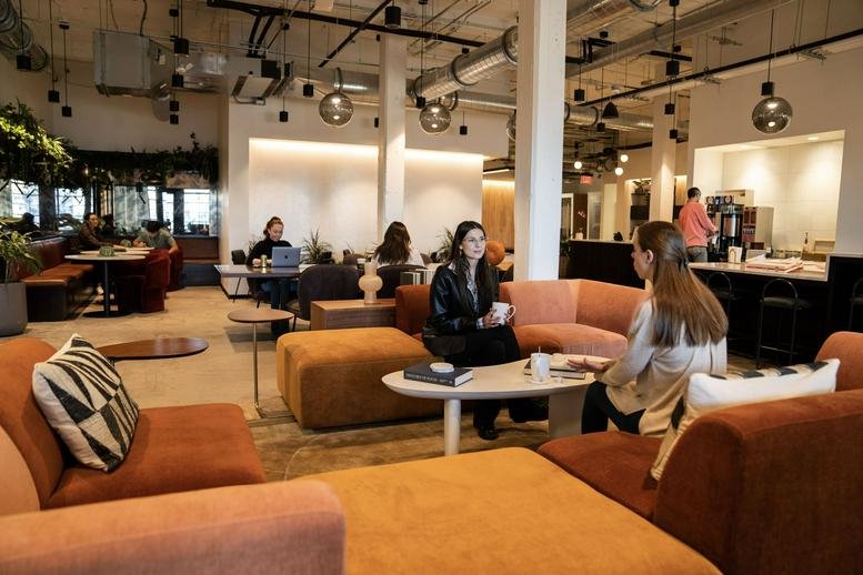 Lively coworking lounge at 209 10th Avenue South, Suite 560 featuring plush orange seating and people socializing.