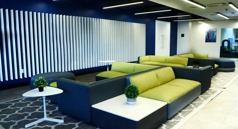 Lounge area at 2098 Gaither Road with lime green sectional sofas and a blue feature wall.