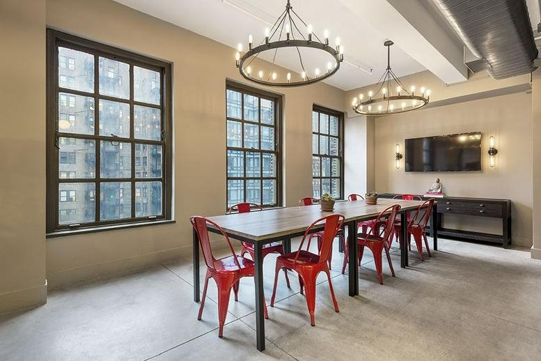 Bright conference room at 21 West 46th Street, Midtown, New York City featuring red chairs and large windows.
