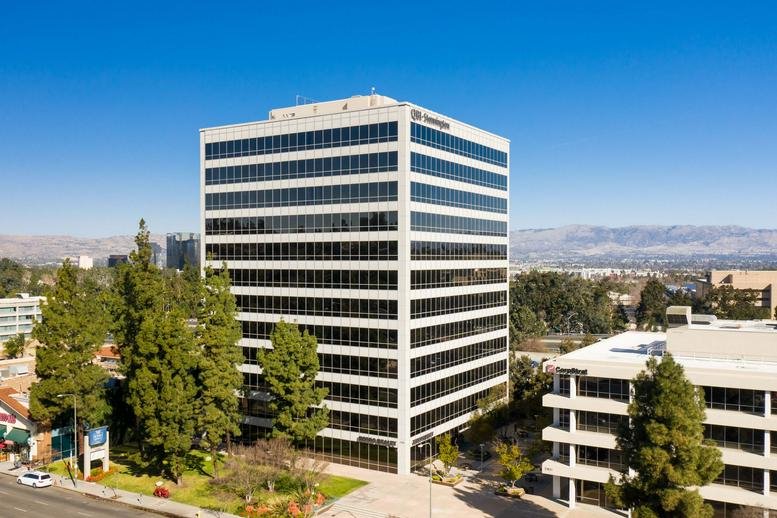 Exterior view of the white high-rise Woodland Hills Corporate Center building under a clear blue sky.