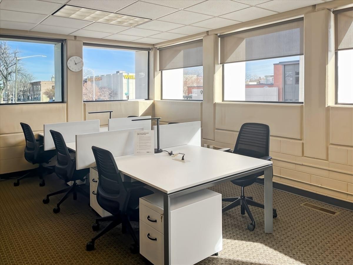 Bright workspace at 214 South 3rd Street, 1st Floor featuring four white desks, black chairs, and large windows.