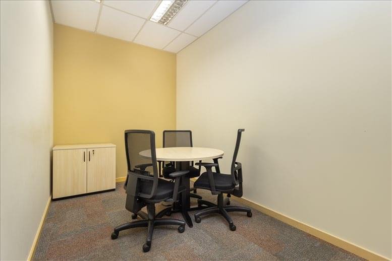 Small private meeting room with a round table and grey mesh chairs.