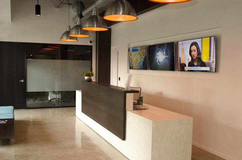 Reception area with a modern wood-paneled desk and overhead industrial pendant lights at 22211 Interstate Highway-10 West.