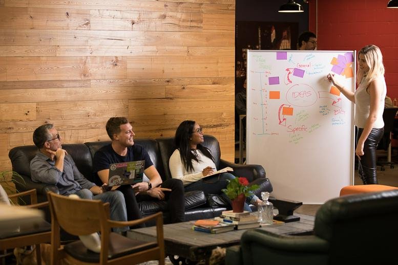 Lounge area at 229 Niagara Street featuring wood-paneled walls and a person writing on a whiteboard.