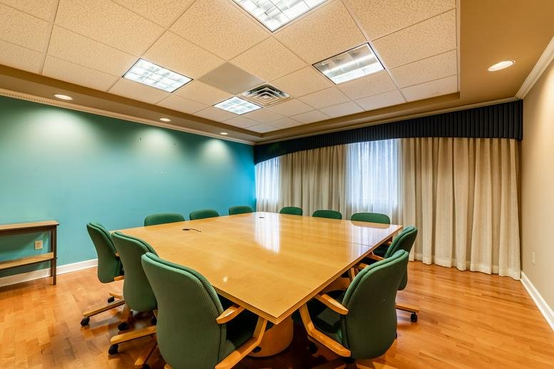 Spacious boardroom at 23 Maiden Lane with a large wooden table and teal feature wall.