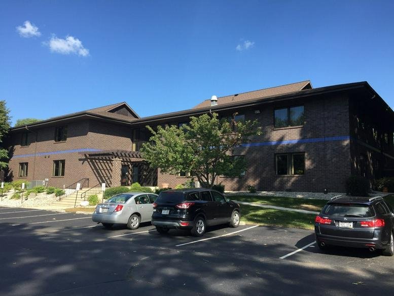Two-story brick office building exterior under a clear blue sky.