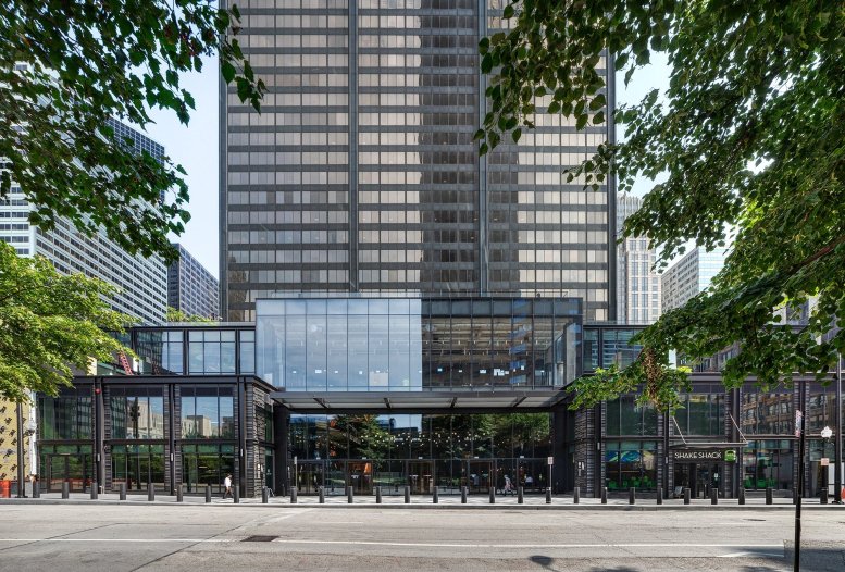 The modern glass and steel entrance of 233 South Wacker Drive framed by lush green trees.