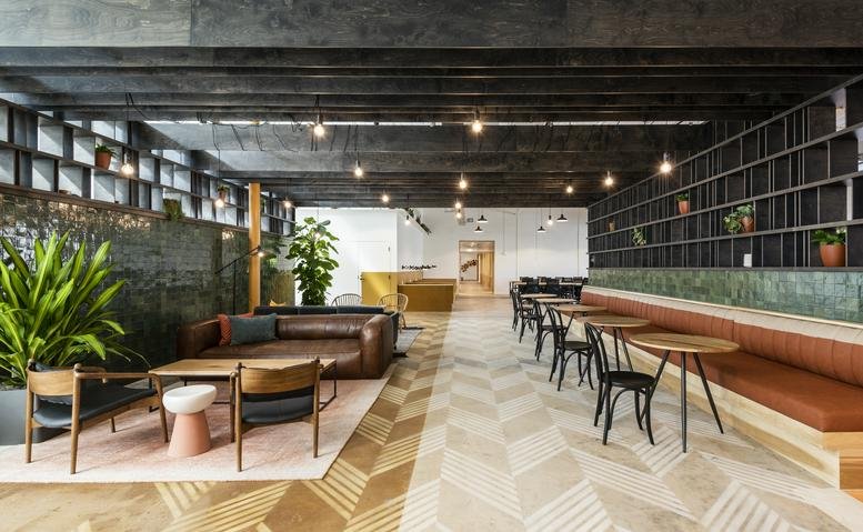 Spacious communal lounge at 2339 Commerce St with a leather sofa, café seating, and dark wood ceilings.