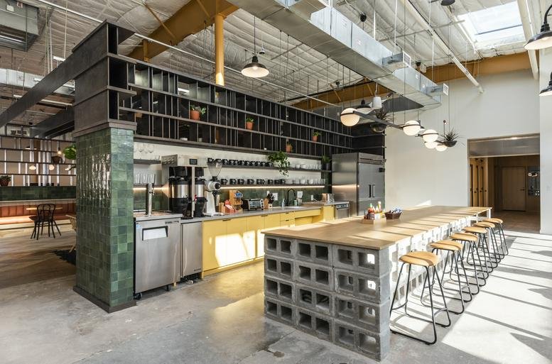 Modern cafe area at 2339 Commerce St with a concrete block bar, barstools, and high industrial ceilings.