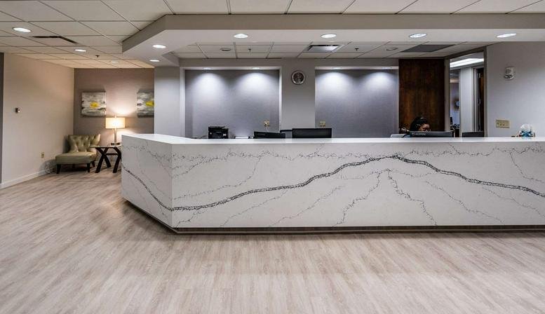 Bright reception area at 235 Peachtree Street, Suite 400 with a marble front desk and neutral tones.