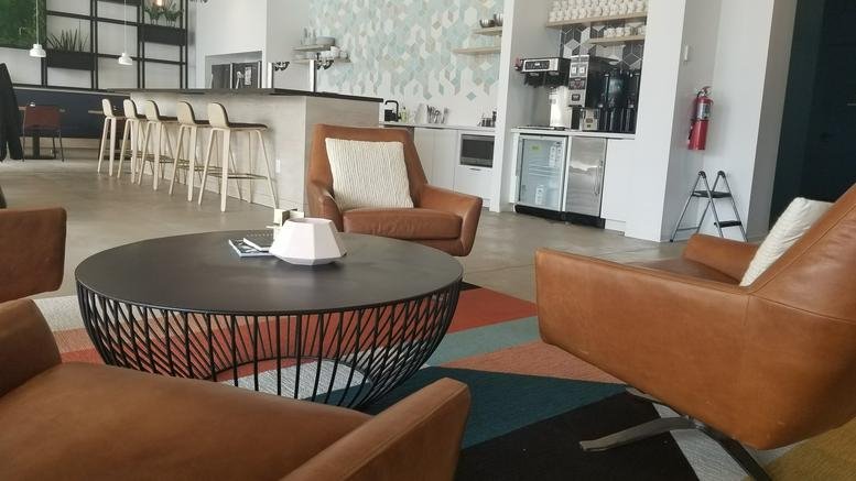 Spacious lounge at 2400 Old Brick Rd with leather armchairs, a wire-frame coffee table, and a modern bar area.