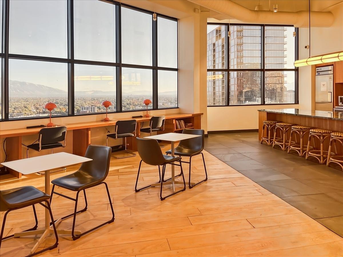 Communal break area with high-top seating, cafe tables, and expansive floor-to-ceiling windows.