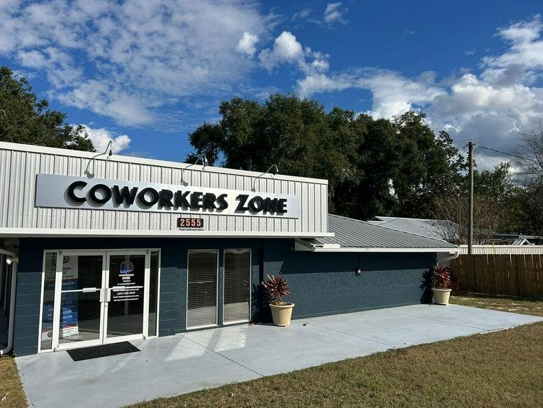 Exterior view of the Coworkers Zone building entrance with blue facade and white siding.