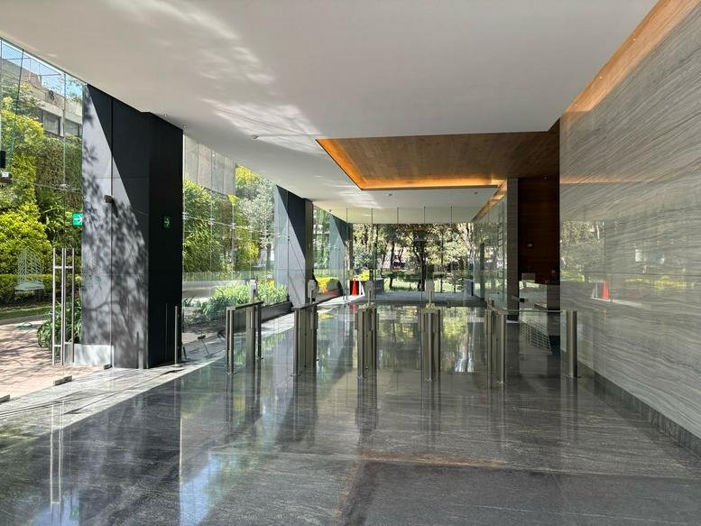 Polished marble lobby at 27, Viaducto Rio Becerra, Escandón I Sección, Mexico City with security turnstiles and glass walls.