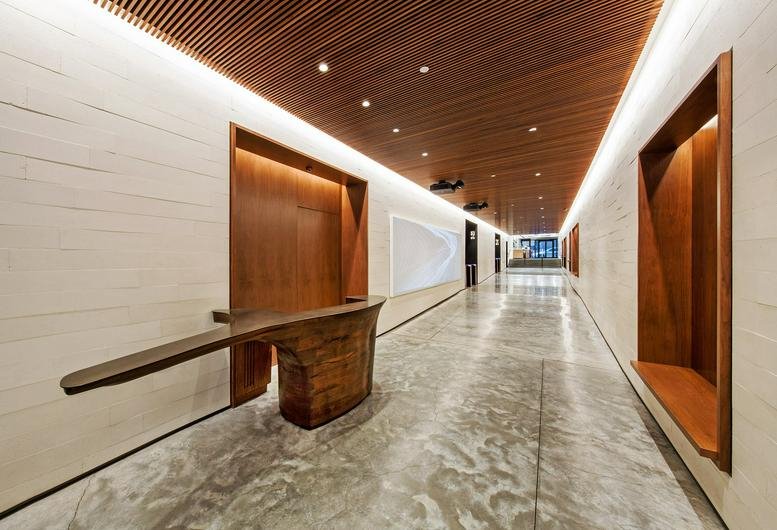 Modern lobby at 30 Broad Street with a sculptural wood reception desk and warm slatted ceiling.
