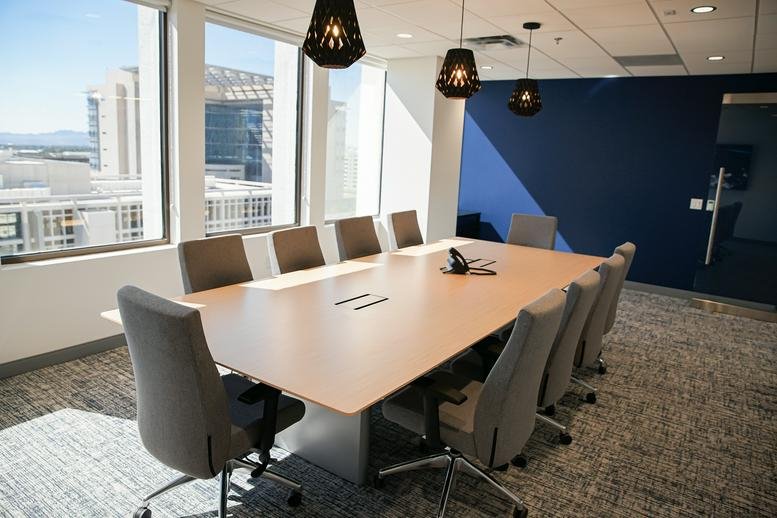 Spacious boardroom with a light wood table, grey chairs, and a deep blue feature wall.