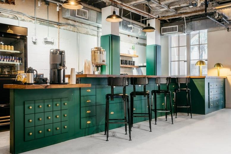 Spacious communal cafe area at 300 Southwest 1st Avenue, Suite 155, with a green bar and wood counters.