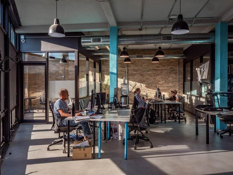Spacious industrial coworking space at 3033 North Clark Street with exposed ductwork and blue pillars.