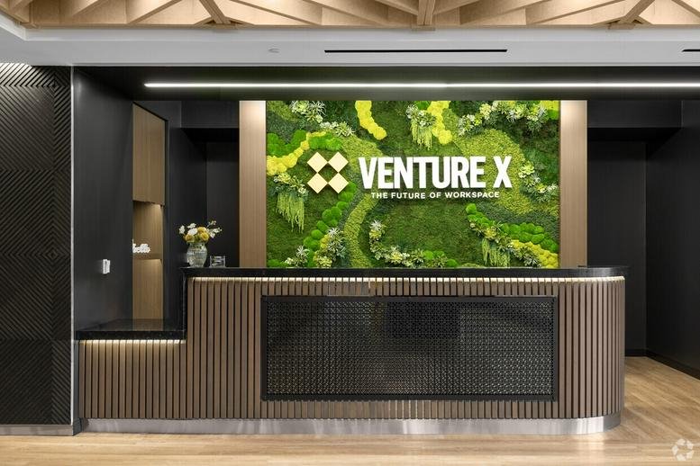 Modern reception desk at 3060 Williams Drive with a vibrant green moss feature wall and wood paneling.