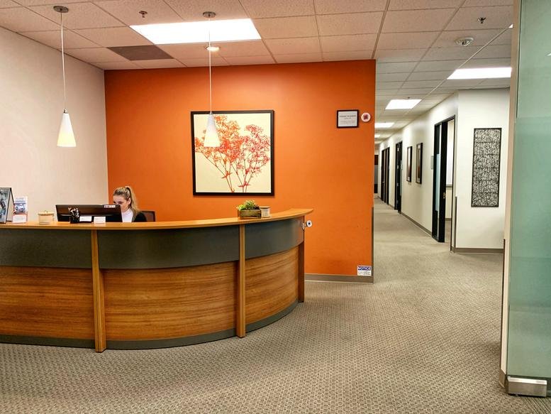 Modern reception desk at 30721 Russell Ranch Road with an orange feature wall and wooden finishes.