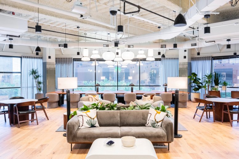 Spacious communal lounge at 3090 Bristol Street, 4th Floor with mid-century furniture and a cluster of pendant lights.