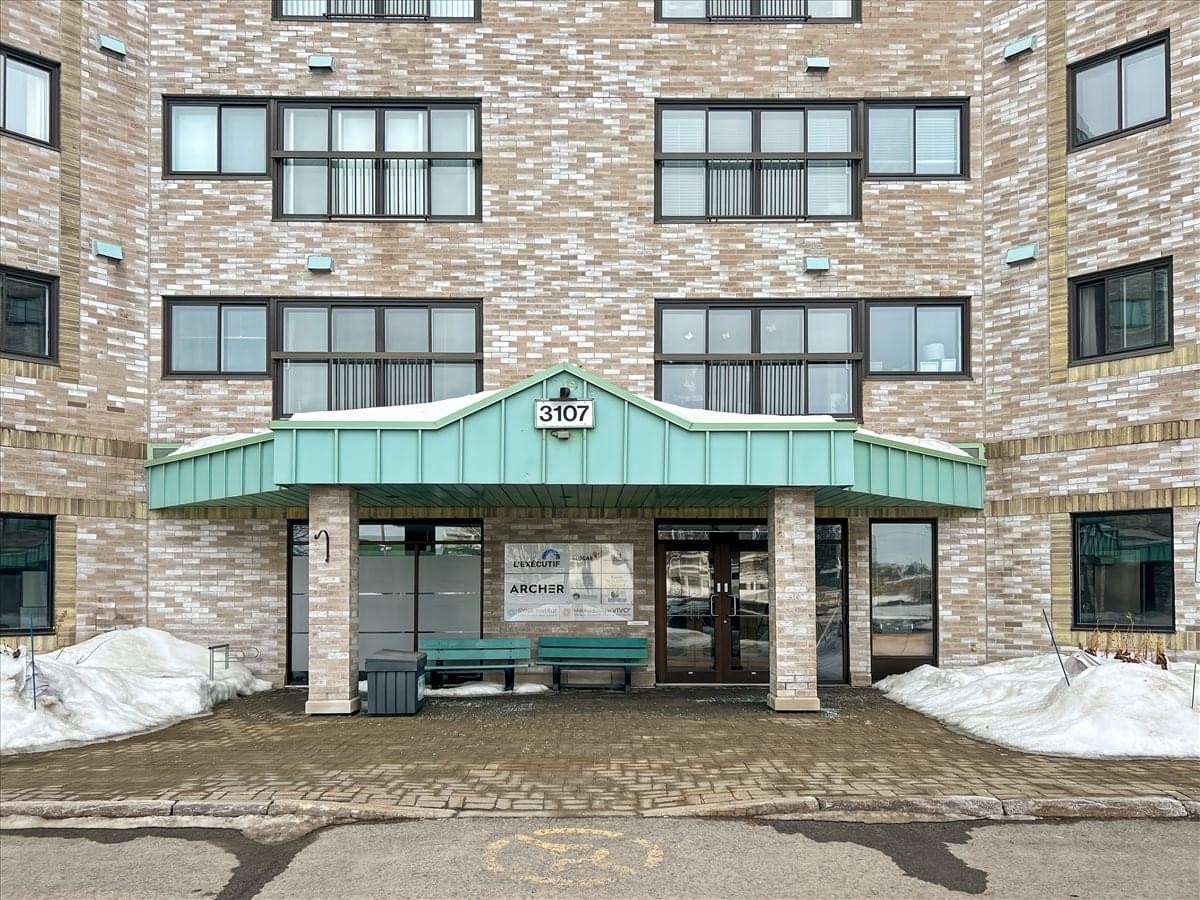 Exterior entrance of the multi-story brick building at 3107 Avenue des Hôtels.