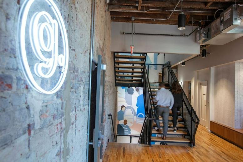 Modern lobby area at 313 East Broad Street, Richmond (Virginia) featuring a neon logo and wooden staircase.