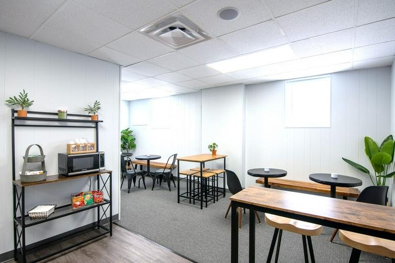 Spacious breakroom at 324 West Main Street, Brighton (Michigan) with café tables and a kitchenette shelf.