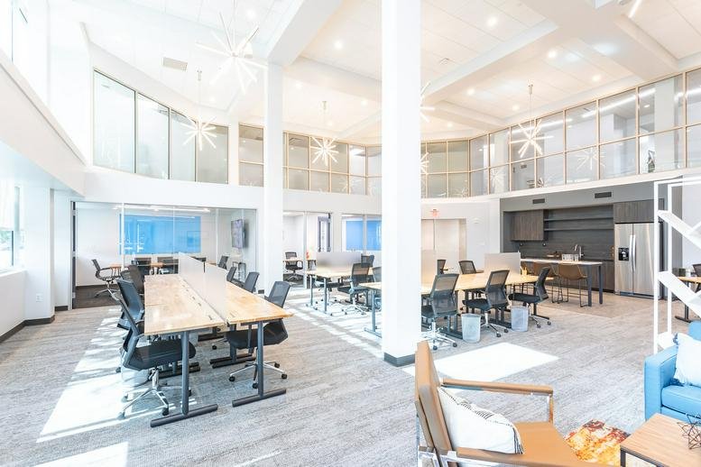 Spacious coworking area with long tables and high ceilings.