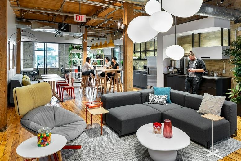Vibrant communal lounge with a large gray sectional sofa and globe lights.