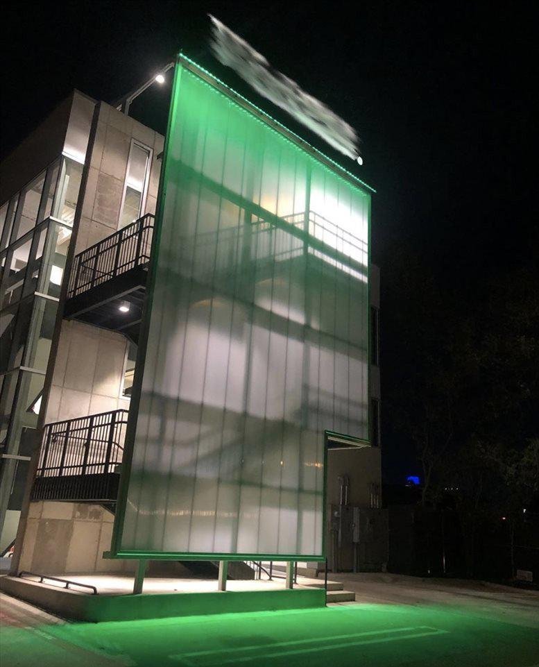 Exterior view of the illuminated glass facade at 3400 Oak Grove Avenue at night.
