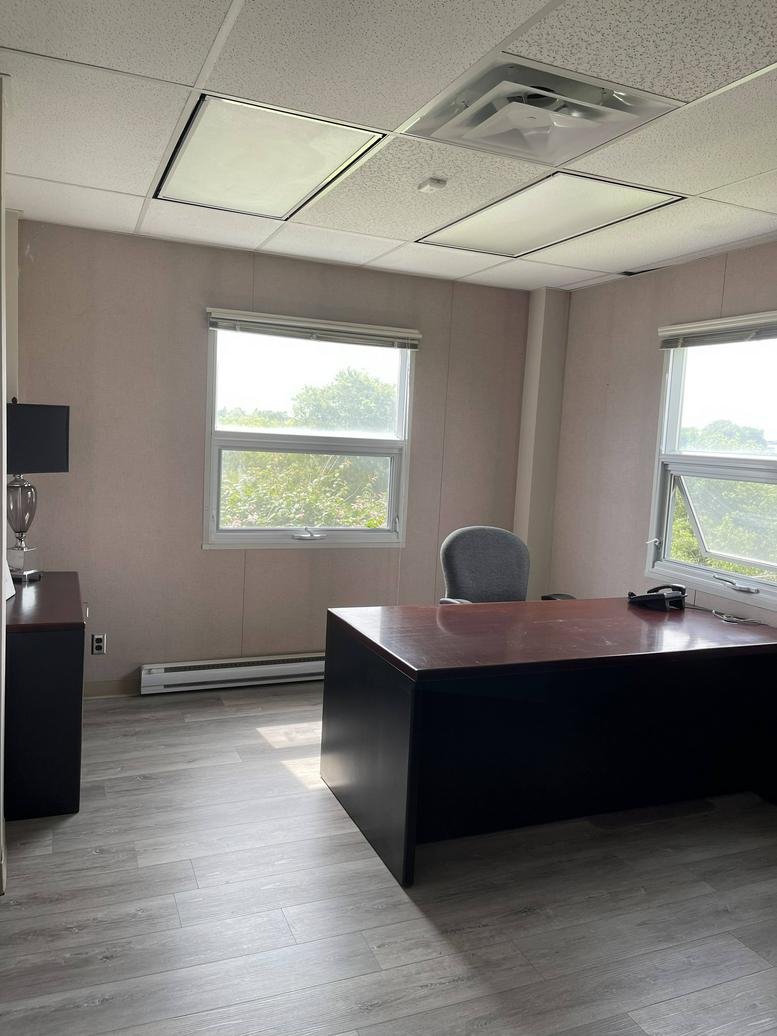 Spacious private office with a large desk and two bright windows.