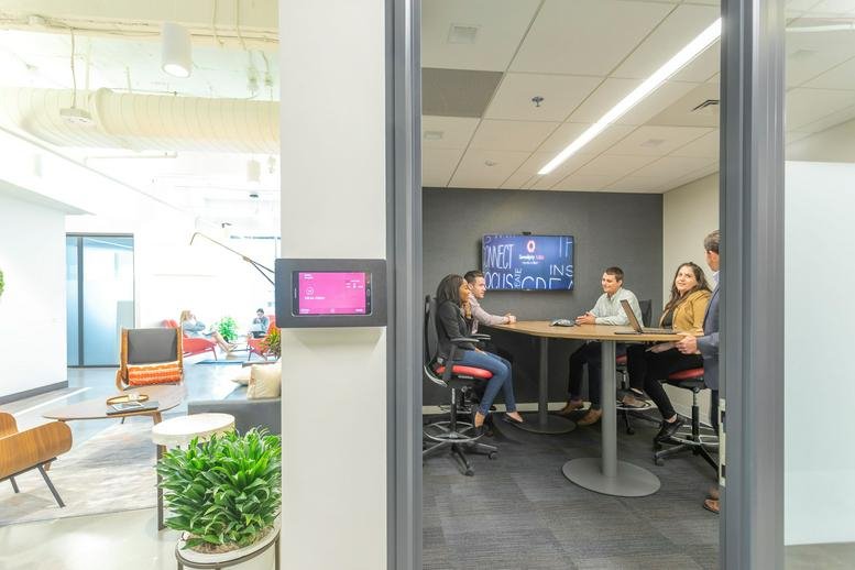Collaborative huddle room with a high table and integrated video conferencing technology.
