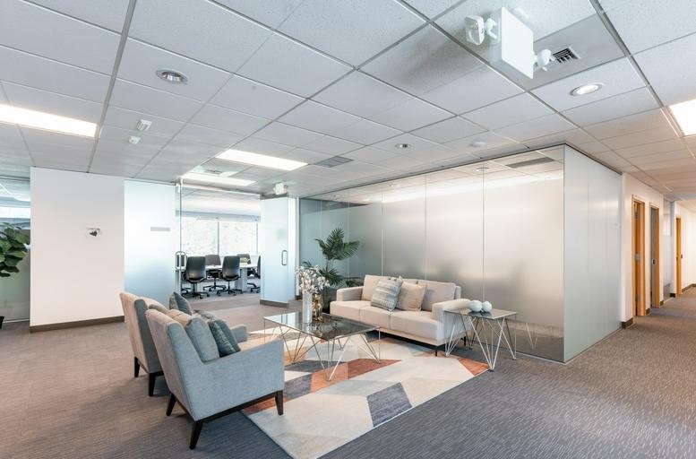 Spacious reception lounge at 3600 136th Pl SE with modern grey armchairs and a decorative rug.
