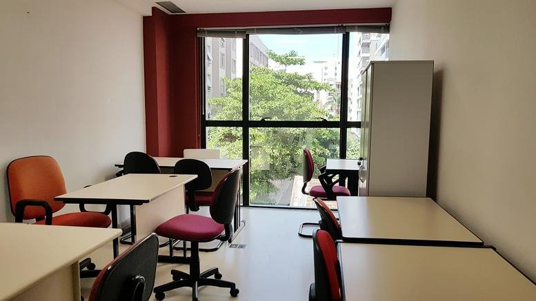 Spacious shared office at 38, Rua Dois de Dezembro, sala 602 with multiple desks and floor-to-ceiling windows.