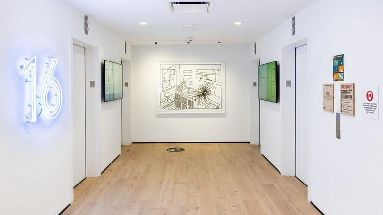 Bright white lobby at 38 West 21st Street, Flatiron District, New York City with blue neon number 16.