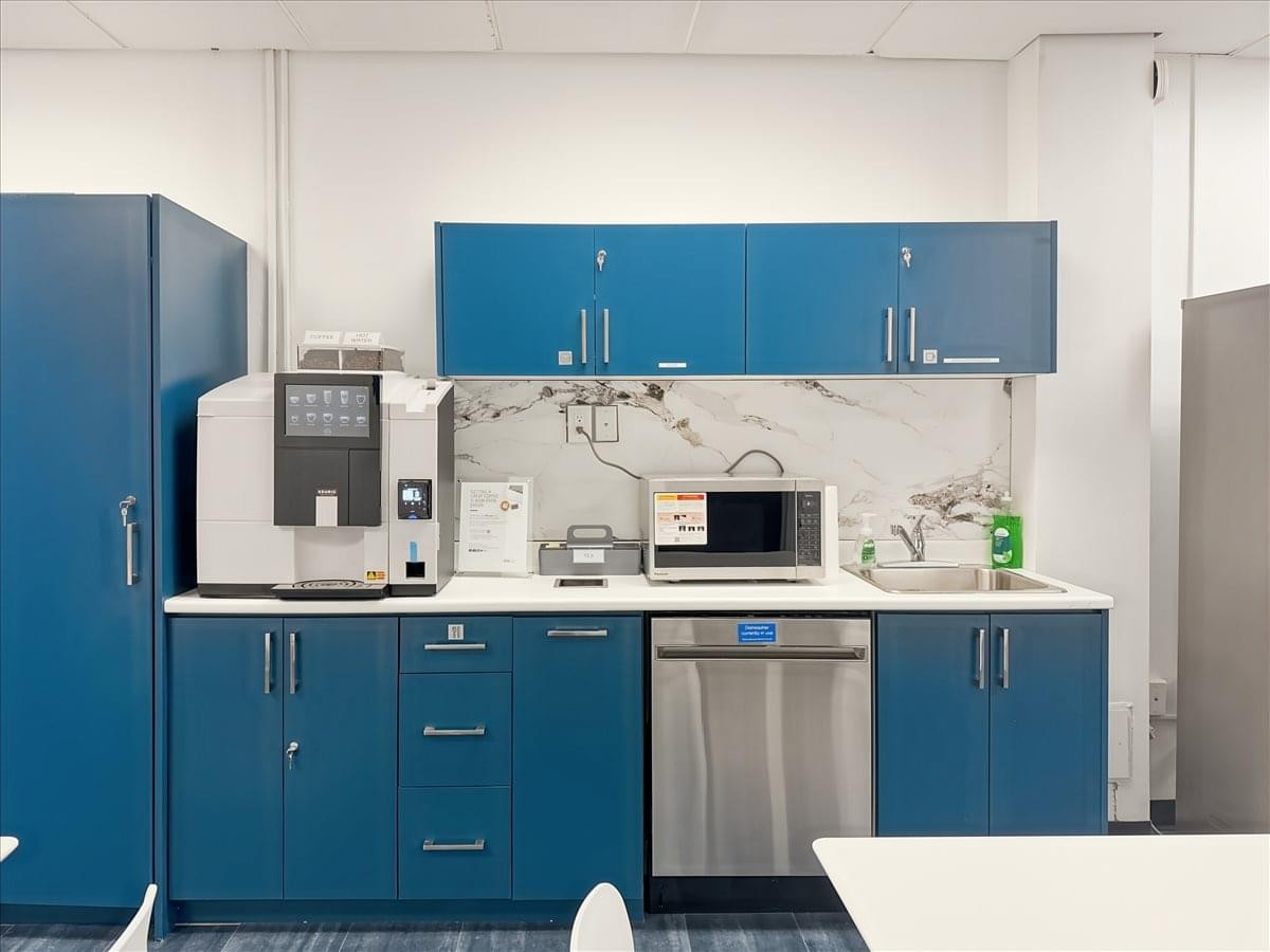 Office kitchen area at 39 Queen St, 3rd Floor featuring blue cabinetry, a microwave, and a coffee machine.