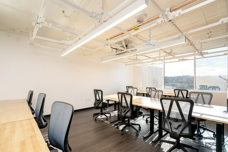 Modern coworking space at 4 West 4th Avenue, Downtown, San Mateo, California with rows of wooden desks.