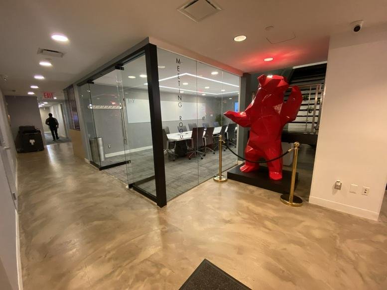 Office hallway featuring a large red bear sculpture and a glass-walled conference room.