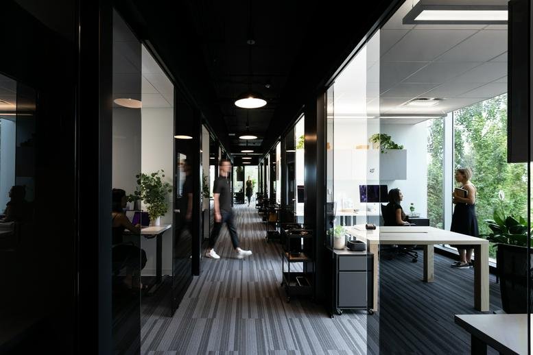 A sleek dark corridor at 400, 22 East 5th Avenue leading to open workspaces with glass partitions.