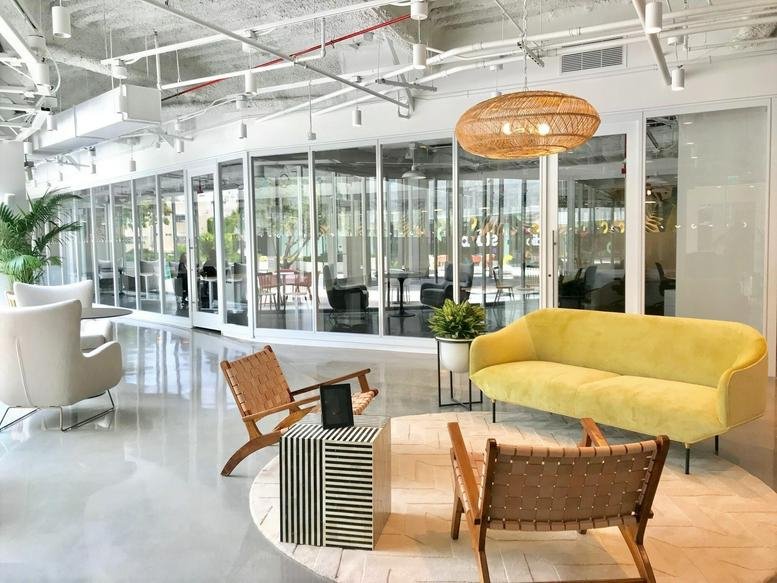 Spacious reception lounge at 407 North Maple Drive with a yellow velvet sofa and wicker chairs.