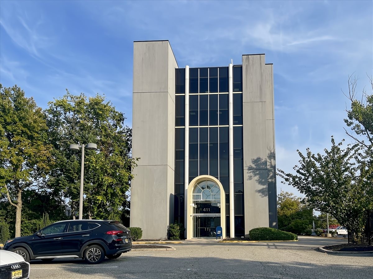 Full exterior view of the gray office building with vertical glass strips.