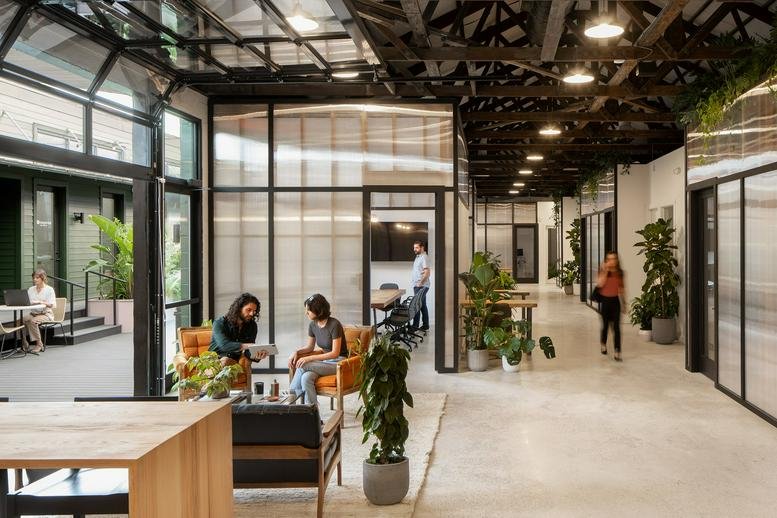 Spacious communal lounge at 4157 St Louis Street with high ceilings, exposed trusses, and warm wooden furniture.