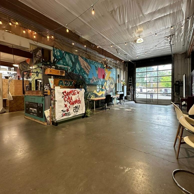 Spacious industrial coworking area at 417 SE 11th Avenue with high ceilings and a colorful mural.