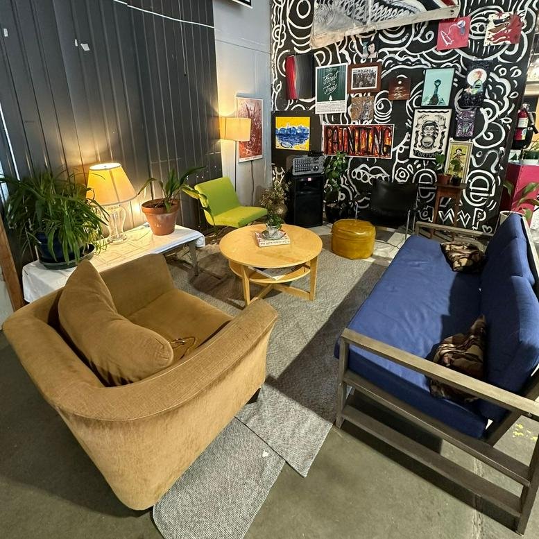 Eclectic lounge area at 417 SE 11th Avenue featuring a blue sofa, armchairs, and art-covered walls.