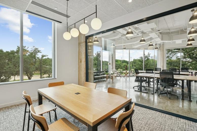 Bright glass-walled office at 4201 Main Street featuring a long wooden table and sphere lights.
